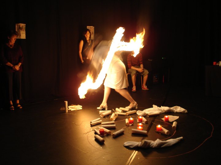 a women dressed in white has fire for fingers reaches to touch a scroll on the ground